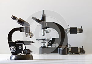 Two black vintage microscopes, side view