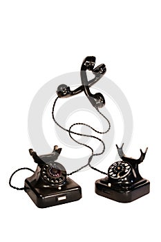 Two black vintage telephones entangled