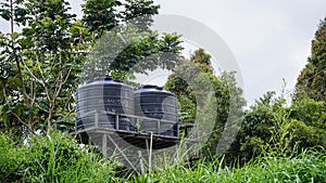 two black water tank surrounded by green trees