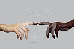 Two black and white hands touch each other with their fingers on a gray isolated background. The concept of interracial