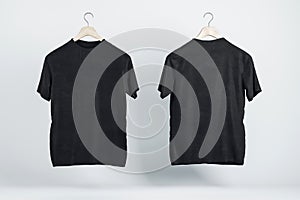 Two blank black t-shirts on wooden hangers with copyspace for your logo on abstract light background. 3D rendering