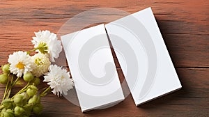 two blank business cards elegantly placed alongside fresh flowers on a wooden table. The flat lay, minimalist style, and