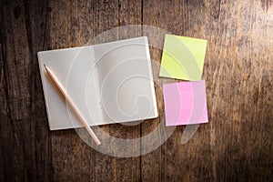 Two blank colorful sticky notes and notebook and pencil