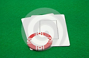 Two blank play cards with casino chip on green