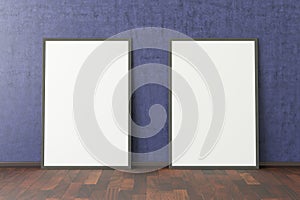 Two blank vertical posters. frame mock up standing on dark parquet floor next to blue wall.