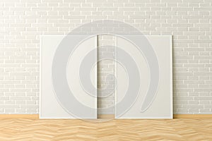 Two blank vertical posters. frame mock up standing on light herringbone parquet floor next to white brick wall. Clipping path arou