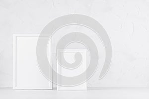 Two blank white different wooden frames in delicate soft light minimal modern white interior on wood desk, copy space. Template.