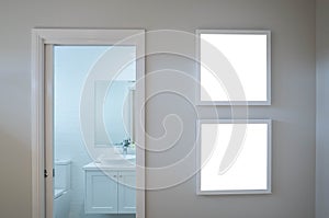 Two blank white square picture/artwork frame mockup template backgrounds on wall at the door of a bathroom/toilet