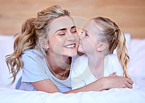 Two blonde caucasian females only looking relaxed and positive while lying in bed together. Young single mother kissing