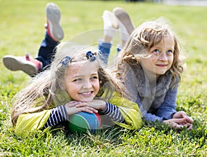 Two blonde girl lie on grass in spring