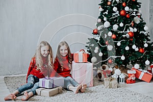 Two blonde girlfriends sisters girls Christmas presents new year tree