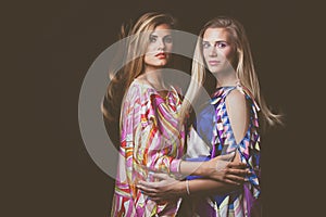 Two blonde young women beauty fashion portrait in colorful silky