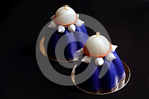 Two blue blueberry mousse desserts with white chocolate and meringues