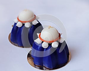 Two blue blueberry mousse desserts with white chocolate and meringues