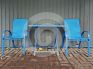 Two blue chairs around a table in a street cafe outside