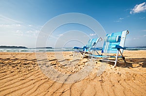 Two blue chaise-longues are on the sand ocean beach photo