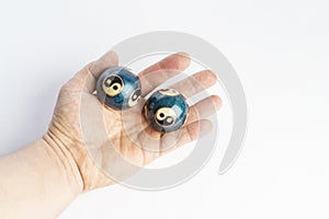 Two blue chinese yin yang balls in hand on white background.