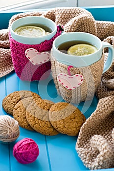 Two blue cup of tea in knitted sweater with hearts felt standing