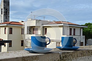 Two blue cups of coffee with panoramic view of a city in background. on the balcony against the backdrop of the old