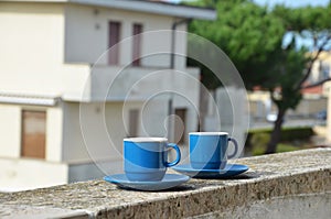 Two blue cups of coffee with panoramic view of a city in background. on the balcony against the backdrop of the old