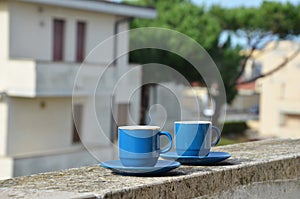 Two blue cups of coffee with panoramic view of a city in background. on the balcony against the backdrop of the old