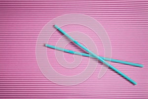 Two blue drinking straws on a pink background, without a plastic Cup