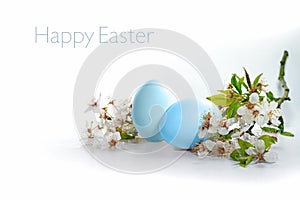 Two blue eggs and a branch of wild flowers on a white background, text Happy Easter, seasonal holiday greeting card, copy space,