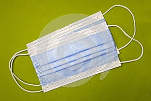 Two blue medical masks on a green textured background close up