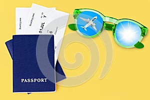 Two blue passports, boarding pass, flight ticket, sunglasses, airplane, sun, blue sky, yellow background, summer holidays, travel