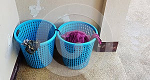Two blue plastic baskets of used laundry put in corners of the room with copy space.