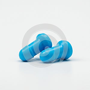 Two blue plastic objects, resembling small blueboard push pins, lie on a white