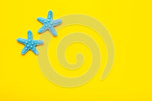 Two blue plastic starfishes on a yellow background