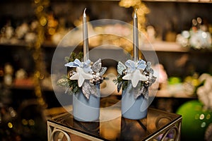 Two blue vase with christmas decor composition of fir-tree branches, toy stars, silver leaves and toys, and candles