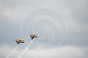 Two Blue and Yellow Biplanes Flying, Together Upwards