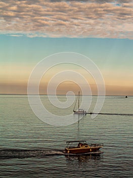 Two boats crossing around on the Adrian sea with clouds and sunset