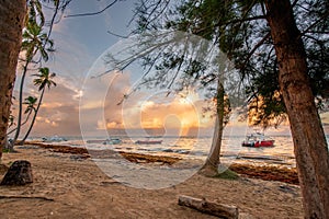 two boats are docked on the beach in the sand during sunset