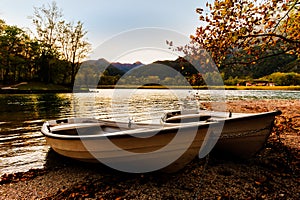 Two boats on the lake shore at sunset.