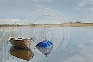 Two boats in a river, cloudy sky.