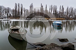 Two boats on the river on a winter morning with reflection in the water