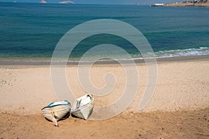 Two boats on sandy shore with blue sea water