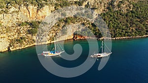 Two boats in sea lagoon near rocky cliff