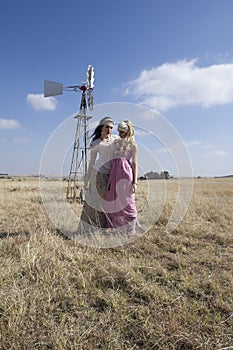 Two bohemian woman posing in field on farm