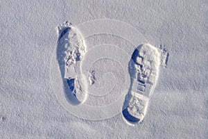 Two boot prints on the surface of the snow