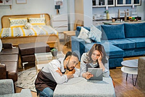 two bored shop assistants using a tablet when the shop is quiet