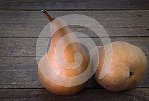 Two Bosc pears on rustic wooden background