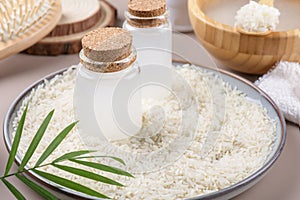 Two bottle with rice water on plate with rice on beige background, beauty recipe home spa, natural skincare preparation