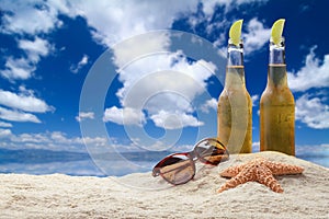 Two bottles of beer with lime on the beach.