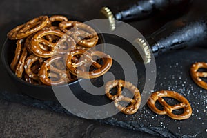Two Bottles of beer with salted bretzel  on dark stone background