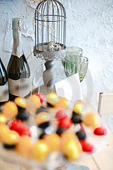 Two bottles of champagne, Easter eggs in a decorative cage and glasses in the background, candies in colored glaze on a glass