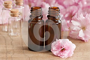 Two bottles of essential oil, with pink japanese cherry blossoms in the background